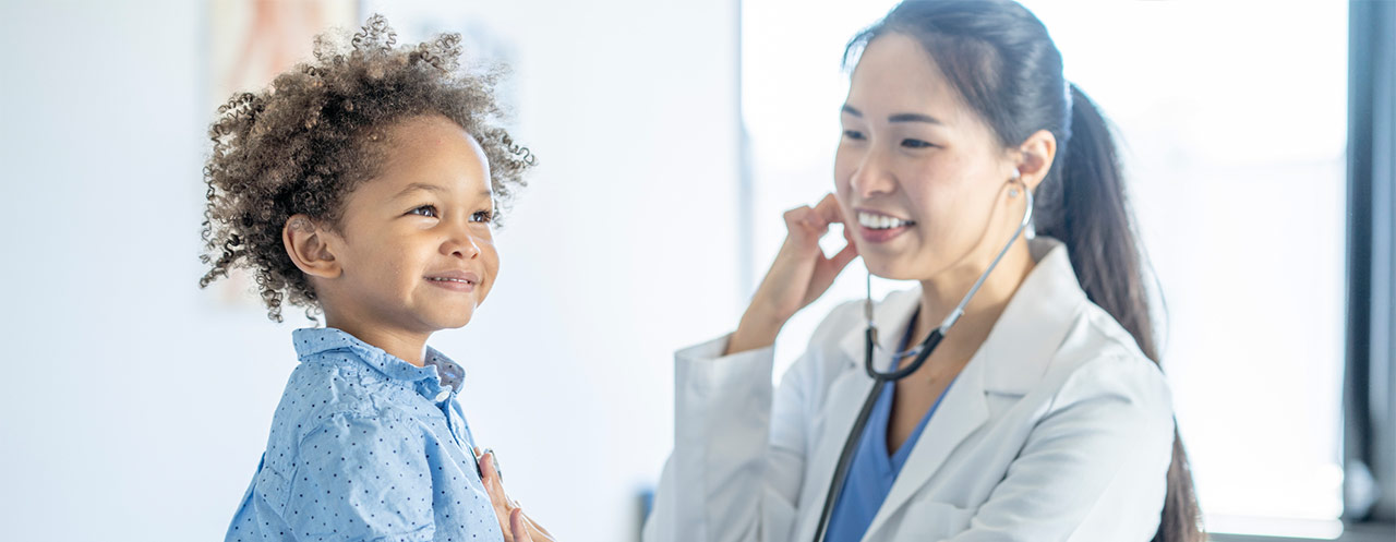 A healthcare provider applying a bandaid to a young patient's arm.